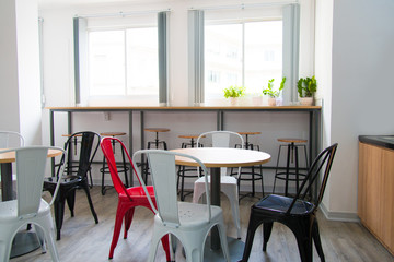 Bar counter at wall and tables with colorful chairs in canteen. Modern coworking space with furniture. Cafe concept