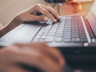 Hands working with keyboard on black laptop computer