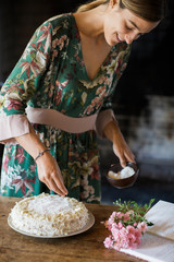 Obraz na płótnie Canvas Smiling young woman garnishing home-baked cake