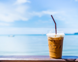 Iced tea with milk on wooden bar on seascape background