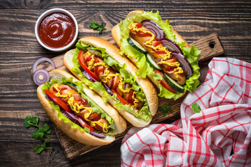Hot dog with fresh vegetables on wooden table.