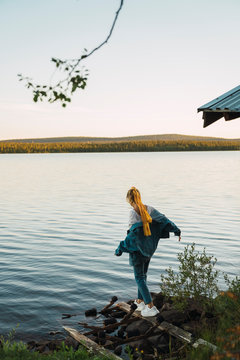 Young woman at a lake, balancing on a plank