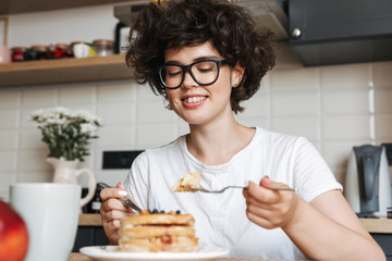 Smiling cheerful girl having tasty breakfast