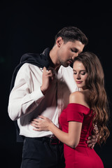 beautiful romantic couple in formal wear hugging isolated on black
