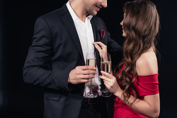 smiling romantic couple holding champagne glasses isolated on black