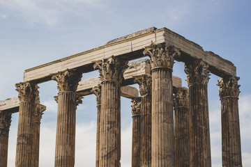 Obraz premium column ancient antique temple ruins foreshortening from below on sky background in vintage pastel color filter, sightseeing and tourist concept, copy space
