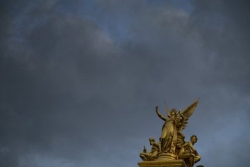 statues opéra de Paris pointant vers un ciel orageux
