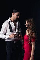 beautiful couple clinking red wine glasses isolated on black