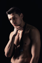 shirtless man posing, looking at camera and touching chin isolated on black