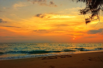 Happy new year concept, 2019 handwriting on sand beach in sunset.