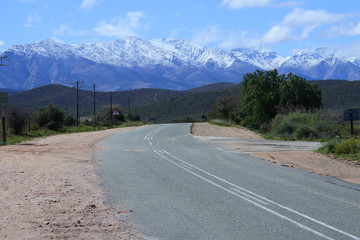 Schneebedeckte Berge und eine Straße durch die kleine Karoo in Südafrika