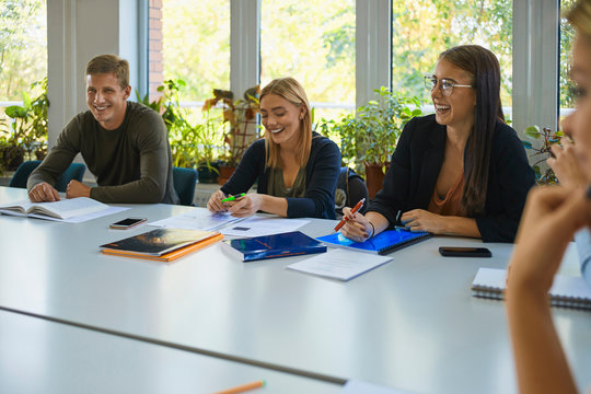 Laughing students sitting at table at university