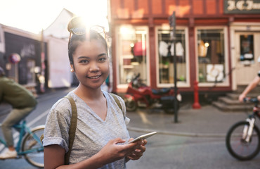 Smiling Asian woman walking in the city using her cellphone