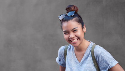 Joyful Asian woman laughing in front of a wall outside