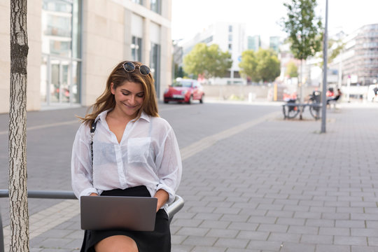 Smiling businesswoman using laptop outdoors