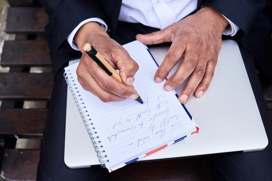 Businessman writing notes in notebook, close-up