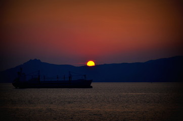 Zachód słońca z przepływającym statkiem transportowym