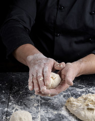 cook making dough balls on a black wooden table