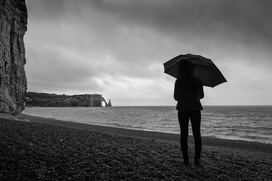 femme avac un parapluie sur la plage &agrave; &eacute;tretat sous la pluie