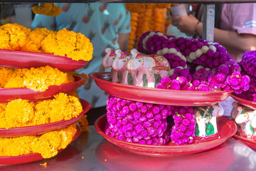 Floral garlands and wooden elephants in red tray for sale at the Erawan Shrine. Bangkok, Thailand.