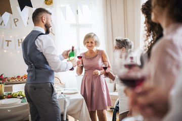 A man pouring guests wine on a indoor family birthday party.