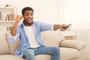 Young african-american man watching TV at home