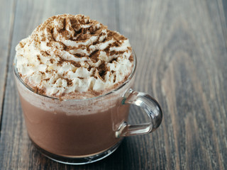 Glass cup with hot chocolate, whipped cream and cinnamon powder. Copy space.