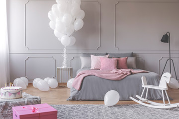 Real photo of a romantic bedroom interior with birthday decorations like balloons, cake and present