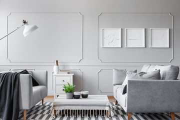 Real photo of an elegant living room interior with a low coffee table, sofas and three graphics