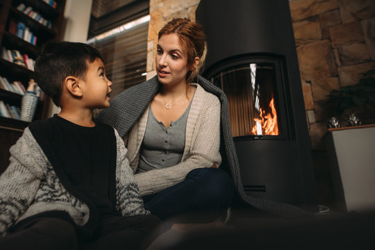 Young mother and son by a fireplace at home