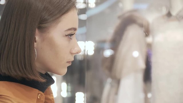 Profile of young woman in reflections of glass case