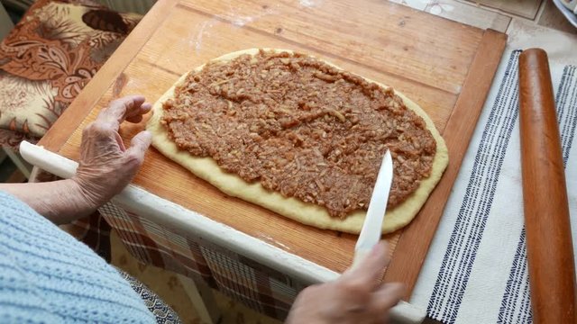 Old woman with wrinkled hands preparing an apple strudel homemade. Senior cooking concept.