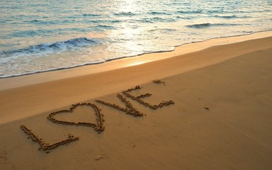 Valentines day concept, love heart shape handwriting on sand beach in sunrise and blue ocean.