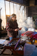Fototapeta na wymiar A man in his DIY workshop to repair an old pedal car