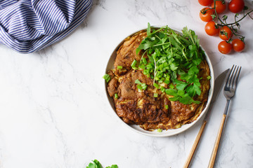 Tortilla omelette with sliced potatoes and herbs on marble table
