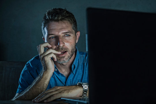 young aroused and excited sex addict man watching porn mobile online in laptop computer light night at home in pornography addiction internet pornographic content