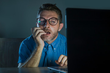 lascivious aroused porn addict man in nerd glasses watching sex movie online late night at laptop...