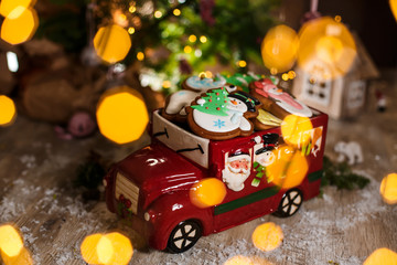 Holiday traditional food bakery. Decorative toy car with christmas Gingerbread cakes in cozy warm decoration with garland lights