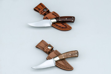 Two sharp finger skinner knives with their custom fit leather sheaths.
