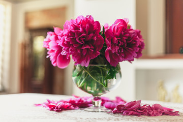 red peonies in glass vase stand on table