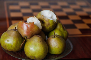 Green pears lie on plate next to chessboard