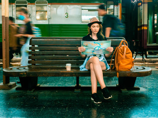 Fototapeta na wymiar travel concept.beautiful traveller girl in train station.girl wating train with moving people.