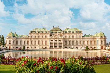 Obraz premium Belvedere palace at sunny day with reflection in a pond and flowers on foreground.