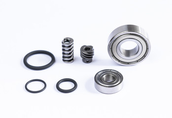Close up view of set spare parts is bearing with tire ring and spring are small placed on white floor.