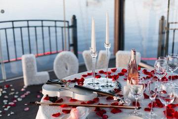 Romantic Valentine day dinner with champagne, roses, rose petals and violin