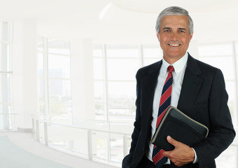 Fototapeta premium Businessman in high key office setting holding a small notebook