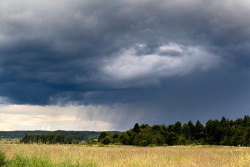 Obraz premium Stormy sky over the field and forest