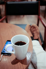 listening to music on a smartphone while drinking coffee alone in a cafe