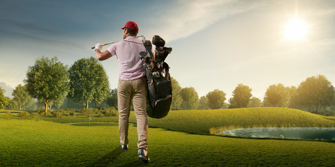 Male golf player on professional golf course. Golfer walking on fairway with golf bag and club....