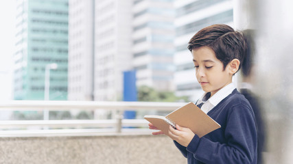 Fototapeta premium young boy reading a books on business district urban, education concept